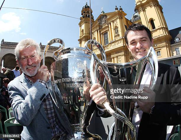 Ambassadors Paul Breitner and Willy Sagnol pose with the men and women's Champions League the trophies in front of the with Feldherrenhalle and...