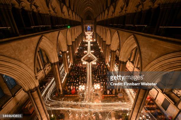 In this combination of two images the interior of Salisbury Cathedral is illuminated by trails of candles carried by choristers and clergy during the...