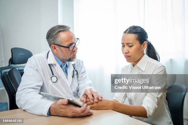 doctors holding hand encouraging and use tablet to describe patient illnesses in hospital. - showing compassion stock pictures, royalty-free photos & images