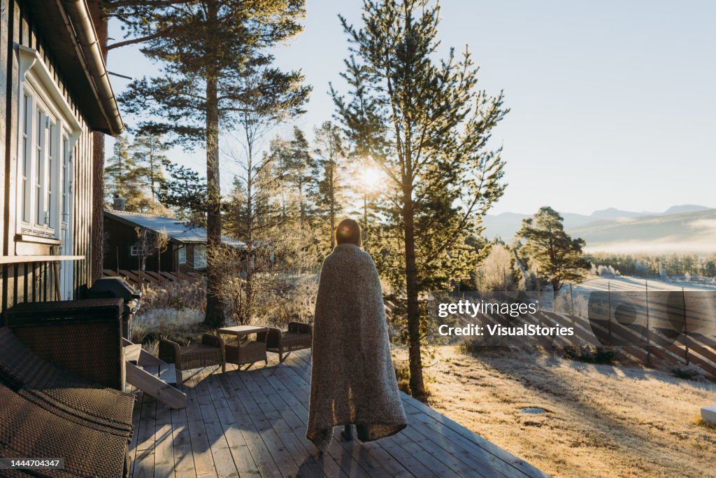 Weibchen beim Sonnenaufgang über die Berge von der Hausterrasse im Wald in Norwegen