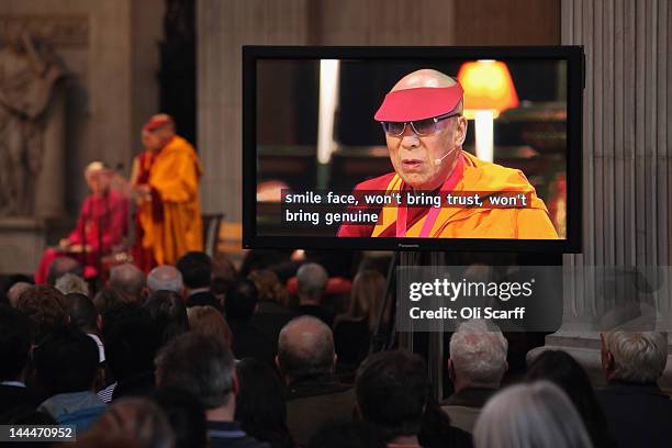 People watch a screen displaying subtitles as His Holiness the Dalai Lama addresses the audience in St Paul's Cathedral after receiving the 2012...