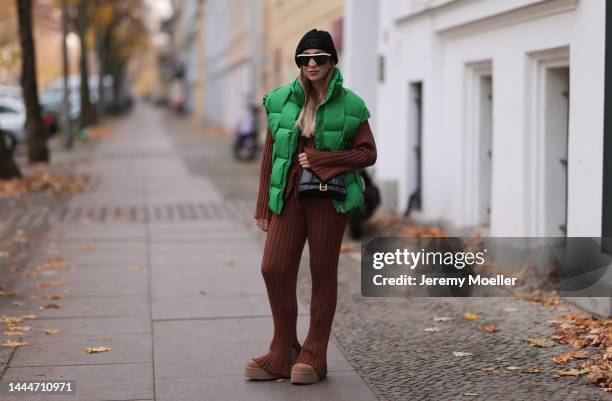 Sonia Lyson is seen wearing Chanel knit black logo hat, Balenciaga black leather hourglass bag, Storets green puffer vest, Bottega Veneta white...