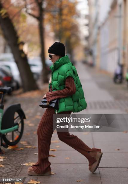 Sonia Lyson is seen wearing Chanel knit black logo hat, Balenciaga black leather hourglass bag, Storets green puffer vest, Bottega Veneta white...