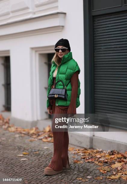 Sonia Lyson is seen wearing Chanel knit black logo hat, Balenciaga black leather hourglass bag, Storets green puffer vest, Bottega Veneta white...