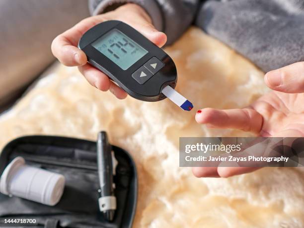 diabetic woman measuring her blood sugar levels using a glucometer - insulina fotografías e imágenes de stock