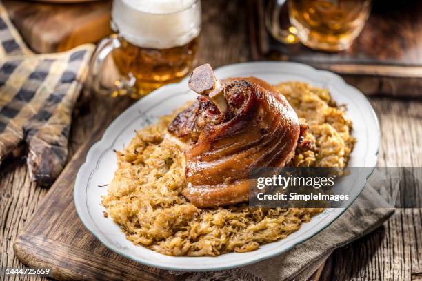 bavarian knee baked together with sauerkraut in an old bowl, draft beer in the background. - chispes - fotografias e filmes do acervo