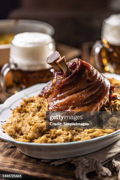 smoked bavarian knee baked together with sauerkraut in an old bowl, draft beer in the background. - duitse gerechten stockfoto's en -beelden