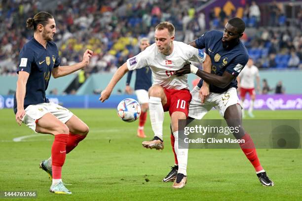 Christian Eriksen of Denmark controls the ball under pressure of Adrien Rabiot and Dayot Upamecano of France during the FIFA World Cup Qatar 2022...