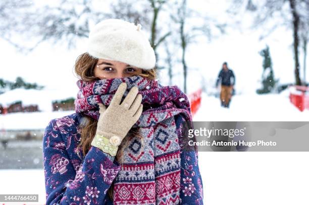 portrait of a blonde woman wearing a beret, jacket and scarf enjoying herself in a snowy park. - purple glove stock pictures, royalty-free photos & images
