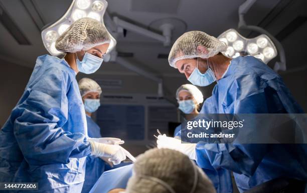 team of surgeons performing a surgery at the hospital - operation theatre stock pictures, royalty-free photos & images