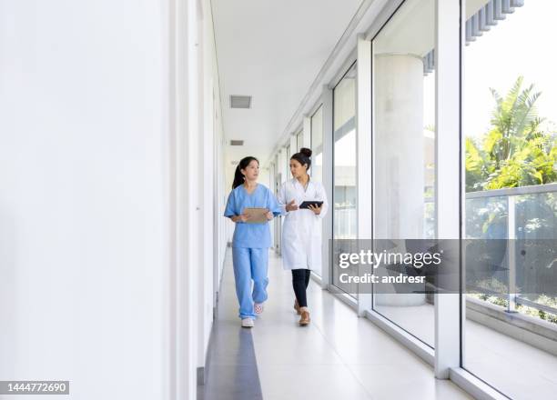 doctor and nurse talking in the corridor of a hospital - civilian stock pictures, royalty-free photos & images