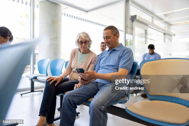 donna anziana con un compagno nella sala d'attesa dell'ospedale - servizio sanitario nazionale britannico foto e immagini stock