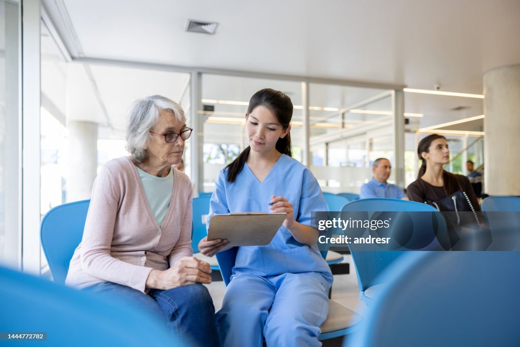 Nurse helping a senior woman fill her registration form at the hospital
