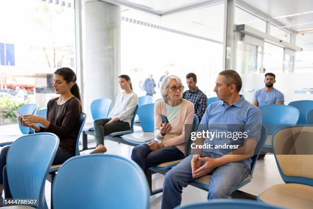 senior woman in the waiting room at the hospital asking for help filling a form - waiting room stockfoto's en -beelden
