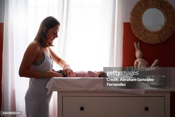 profile photo of a mother changing a diaper to her son - mum changing nappy stock-fotos und bilder