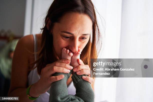 mother kissing the toes of her baby - kissing feet stock pictures, royalty-free photos & images