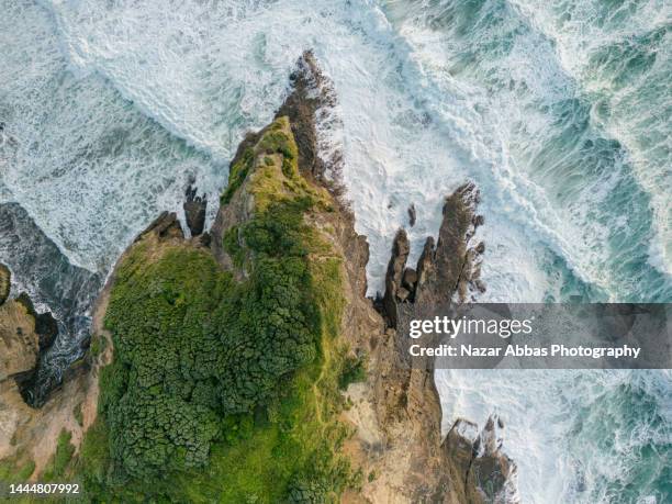 aerial view of waves splashing against rocks. - waitakere city stock pictures, royalty-free photos & images