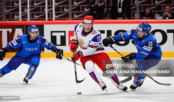 Russia's Denis Kokarev vies for the puck with Italy's Luca Felicetti and Derek Edwardson during a preliminary round ice hockey match at the Ice...