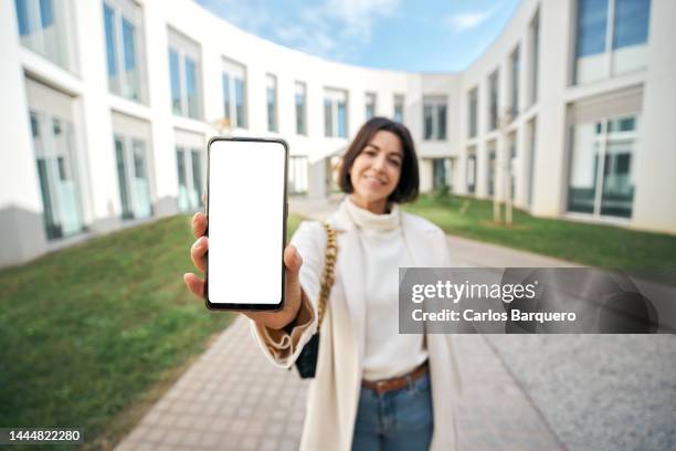 copy space photo of female doctor showing empty white phone screen standing by a new residential buildings. - showing smartphone stock pictures, royalty-free photos & images