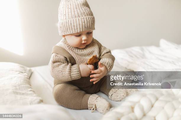 a 5 month old baby boy in cotton knitwear laying on a bed. - wool blanket stock pictures, royalty-free photos & images