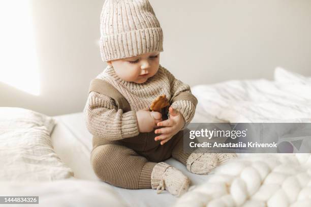 a 5 month old baby boy in cotton knitwear laying on a bed. - baby clothes bildbanksfoton och bilder