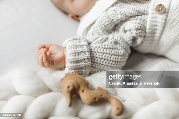 baby's hands in cotton knitwear laying on a bed. - baby cotton wool stock pictures, royalty-free photos & images