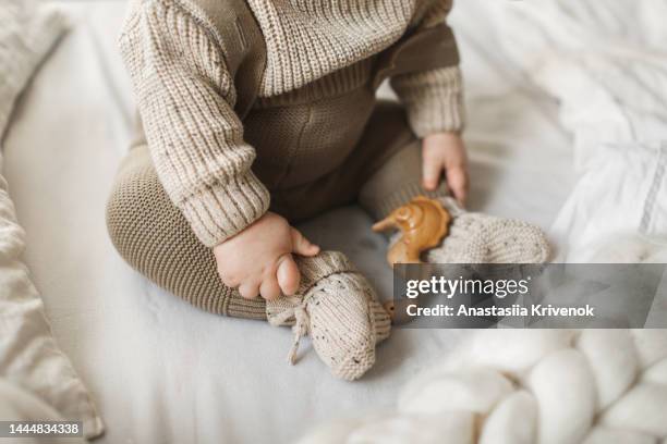 baby's legs in cotton knitwear laying on a bed. - baby cotton wool stock pictures, royalty-free photos & images