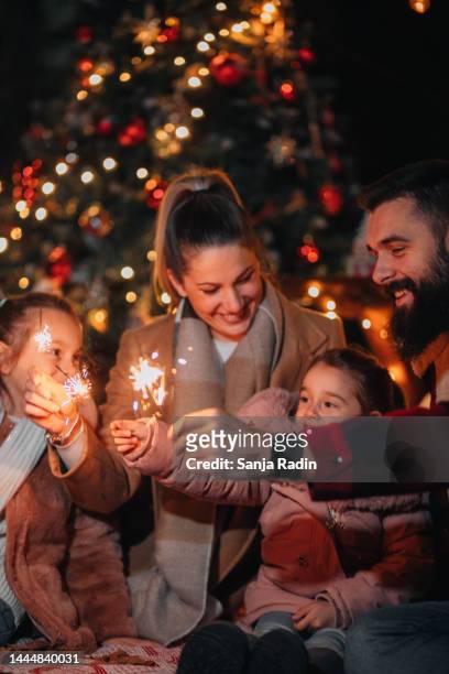 happy family holding sparklers on christmas eve - family new year's eve stock pictures, royalty-free photos & images