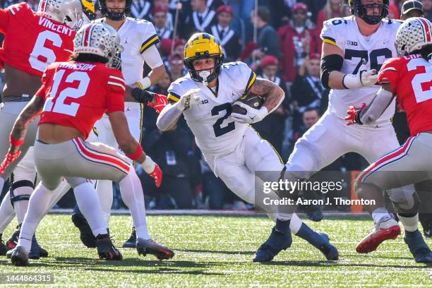 Blake Corum of the Michigan Wolverines runs with the ball as Lathan Ransom of the Ohio State Buckeyes prepares to tackle him during the first half of...