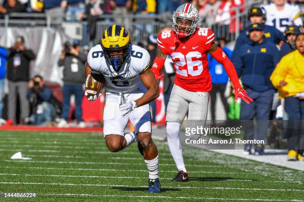 Cornelius Johnson of the Michigan Wolverines runs downfield for a touchdown while chased by Cameron Brown of the Ohio State Buckeyes during the first...