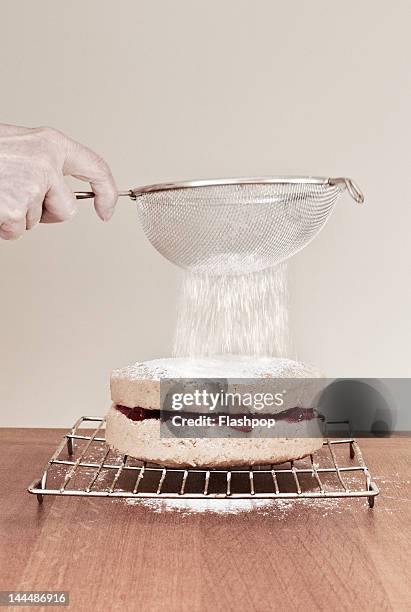 woman sieving icing sugar on top of a cake - sieve stock pictures, royalty-free photos & images
