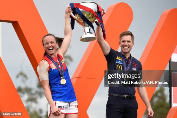 Head coach Mick Stinear and Daisy Pearce of the Demons hold the trophy aloft after winning the AFLW Grand Final match between the Brisbane Lions and...