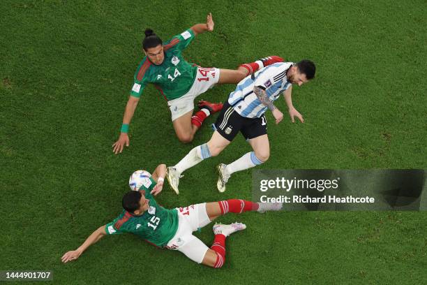 Lionel Messi of Argentina is brought down by Erick Gutierrez and Hector Moreno of Mexico during the FIFA World Cup Qatar 2022 Group C match between...