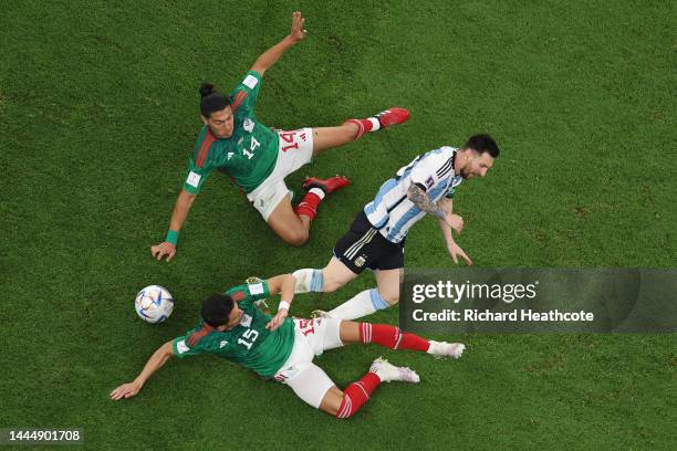 Lionel Messi of Argentina is brought down by Erick Gutierrez and Hector Moreno of Mexico during the FIFA World Cup Qatar 2022 Group C match between...