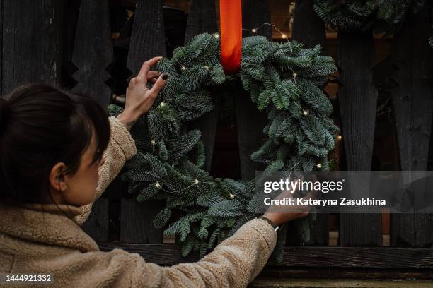 a natural setup with christmas pine wreaths outside a wooden house - decorating the christmas tree stock pictures, royalty-free photos & images