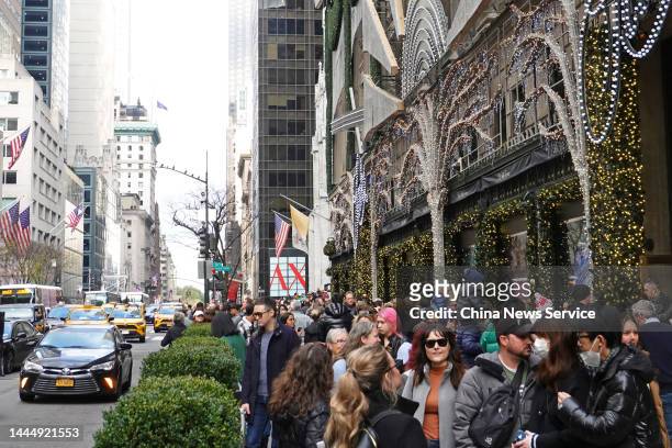 People walk by a shopping mall at the Fifth Avenue on Black Friday on November 25, 2022 in New York City.