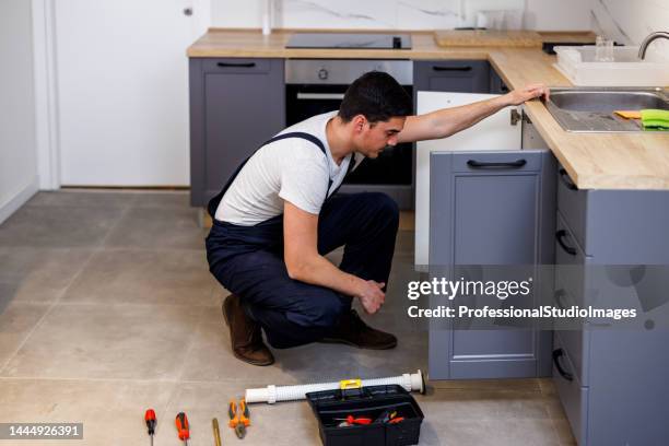 a young man is fixing home appliances with his tools. - looking under sink stock pictures, royalty-free photos & images