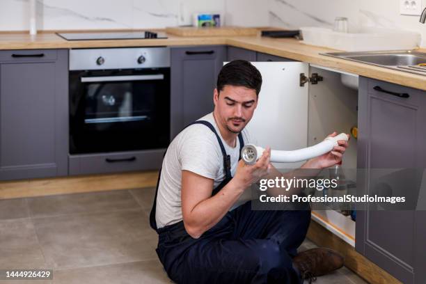 ein jüngerer wartungstechniker arbeitet in der küche. - drain inspection stock-fotos und bilder