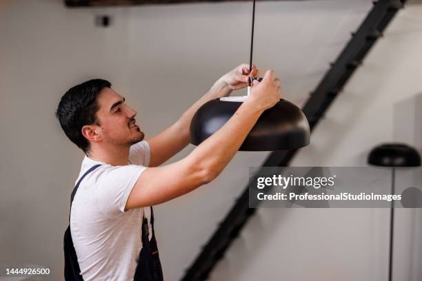 a young man is working at home and fixing the electric lamp. - broken lamp stock pictures, royalty-free photos & images