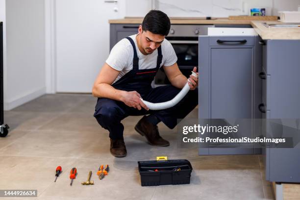 a younger maintenance engineer is working in the kitchen. - looking under sink stock pictures, royalty-free photos & images
