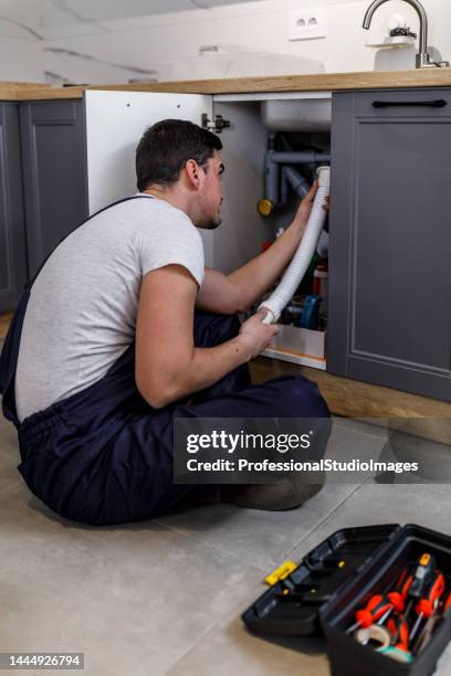 a young man is fixing home appliances with his tools. - looking under sink stock pictures, royalty-free photos & images