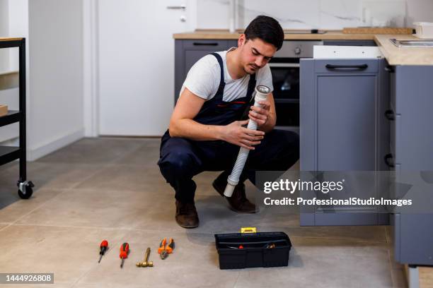 un giovane operaio sta riparando un rubinetto in cucina. - under sink foto e immagini stock