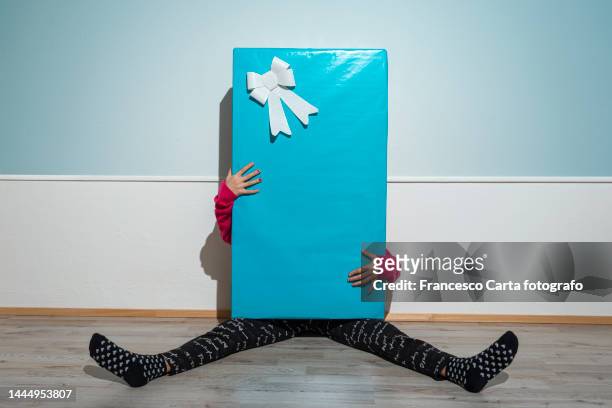 little girl hiding behind a giant gift box - children funny moments stock pictures, royalty-free photos & images