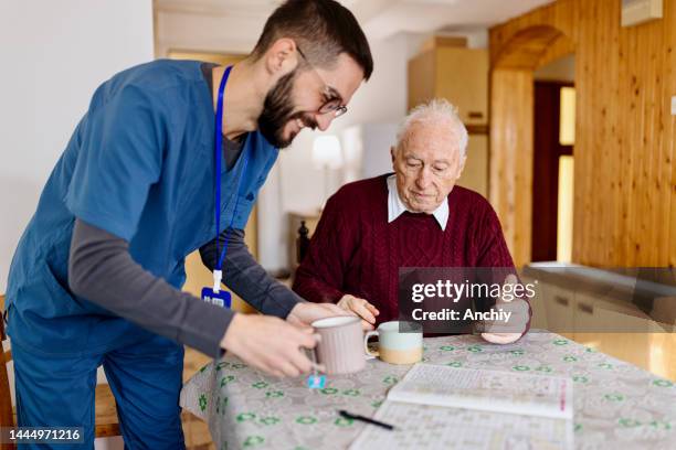 caretaker with senior man enjoying coffee break - assisted living community stock pictures, royalty-free photos & images