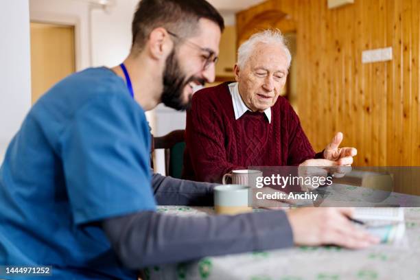 caretaker with senior man enjoying coffee break - social worker stock pictures, royalty-free photos & images