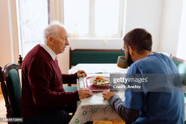 home caregiver caring for a senior man - aged care food stock pictures, royalty-free photos & images