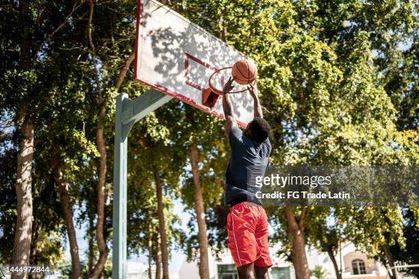 young man doing a jump shot at the basketball court - jump shot stock pictures, royalty-free photos & images