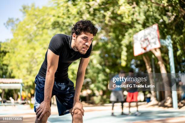 erschöpfter junger mann auf einem basketballplatz - suffocated stock-fotos und bilder