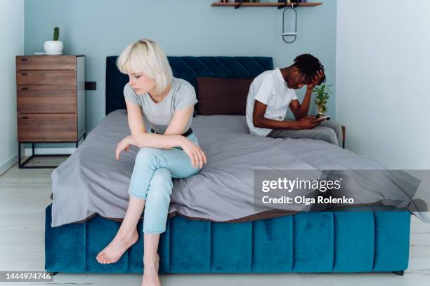 digital addiction, man dependent of social net. interracial romantic couple sit on a bed on different sides, man into smartphone - share my wife photos stock pictures, royalty-free photos & images