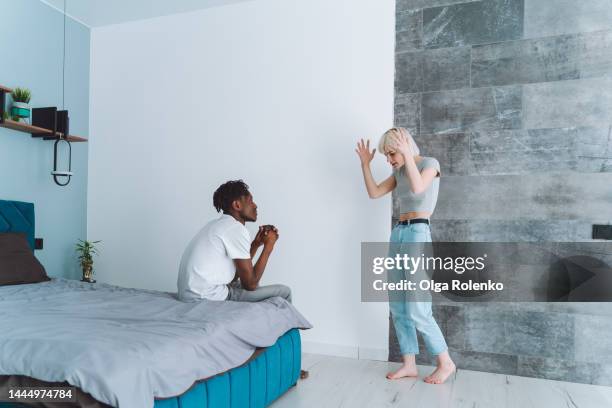 relationship difficulties. young interracial couple arguing, woman screaming at man in bedroom - ehebruch stock-fotos und bilder